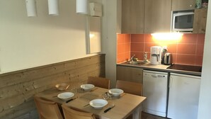 A compact kitchen with a dining area. It includes a sink, a microwave, a coffee maker, and a dishwasher.
