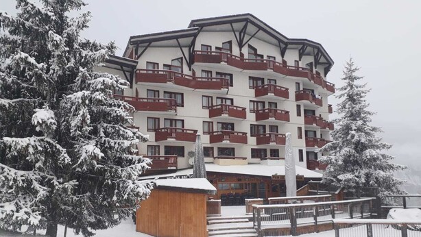 A multi-story hotel with balconies, surrounded by snow-covered trees.