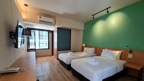 Een hotelkamer met twee bedden, een bureau met telefoon en een aan de muur bevestigde televisie.