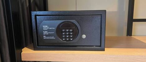 A safe with a keypad, instructions for closing and opening, and a small hole for a key.