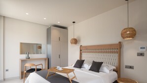 Un dormitorio moderno con una cama grande, mesitas de noche, un escritorio y un espejo.