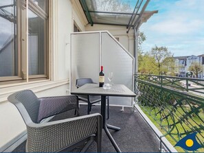 Een balkon met een tafel, stoelen, een fles wijn en een glas.