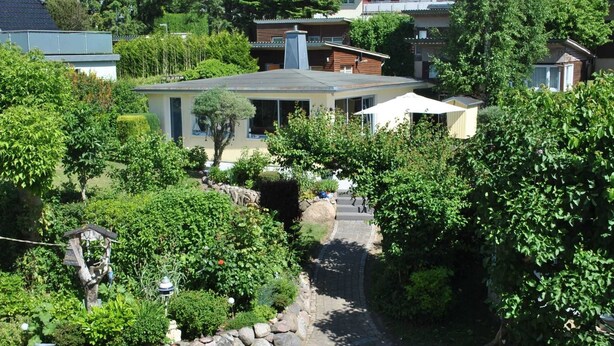 A residential property with a paved driveway, stone wall, and lush greenery. - Holiday house Schlenker (Binz)