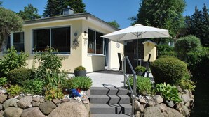 A building with a yellow exterior, large windows, and a covered entrance with steps leading up to it. - Holiday house Schlenker (Binz)