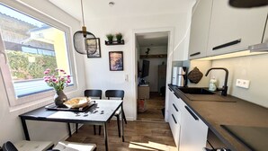 A modern kitchen with a dining area, wooden flooring, and a view of the outside. - Holiday house Schlenker (Binz)
