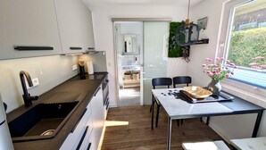 A modern kitchen with a built-in oven, a sink, and a dining area with a table and chairs. - Holiday house Schlenker (Binz)