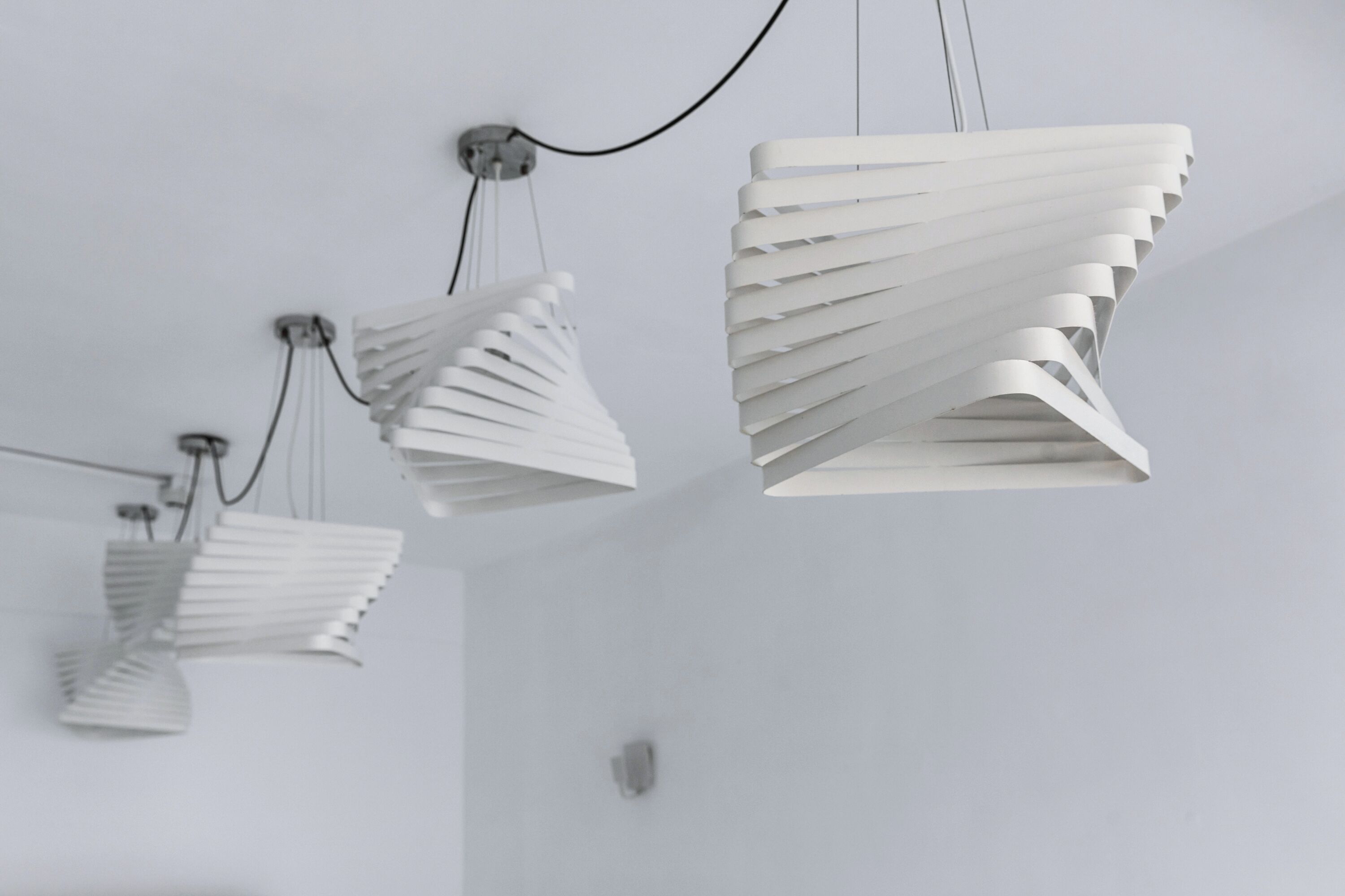 Three white, modern pendant lights with a unique, layered design hanging from the ceiling.