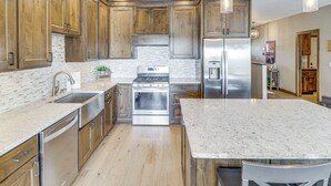 A modern kitchen with wooden cabinets, stainless steel appliances, and a marble countertop. - Spacious 6BR Lake Victoria Retreat w/ Private Dock (Alexandria)