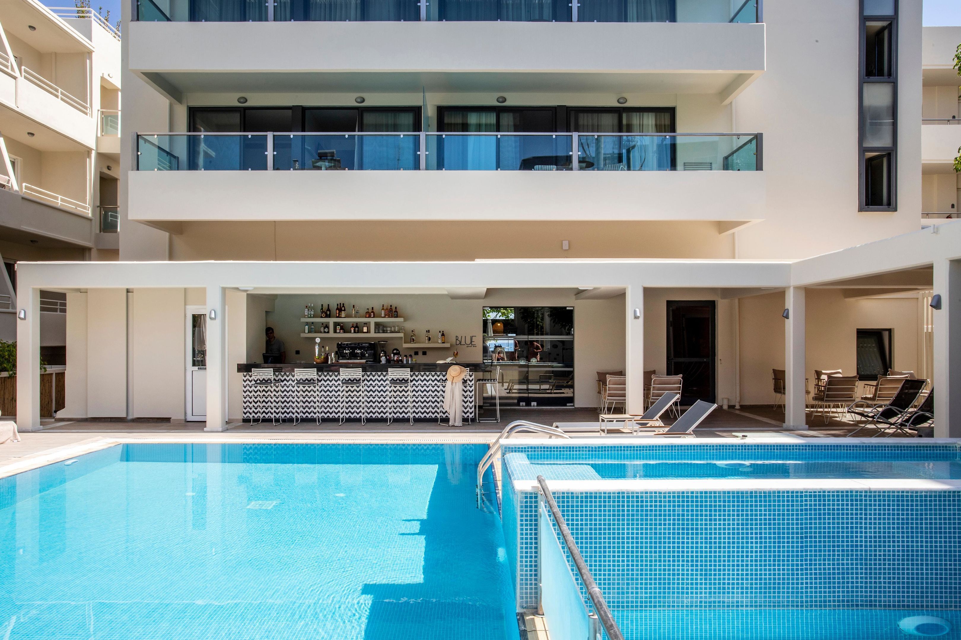 A modern hotel with a pool, a bar area, and a dining space.