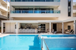 Un hotel moderno con piscina, zona de bar y comedor.