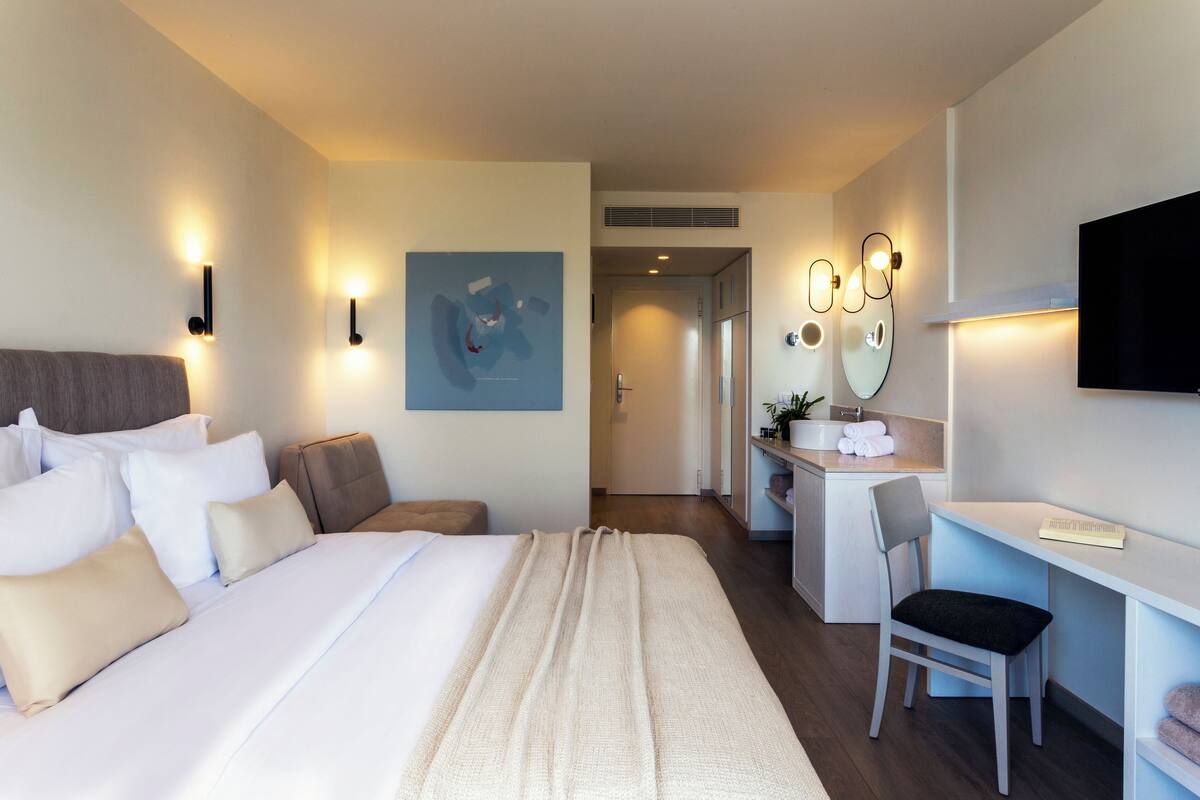 Een moderne hotelkamer met een groot bed, een bureau, een stoel en een televisie.