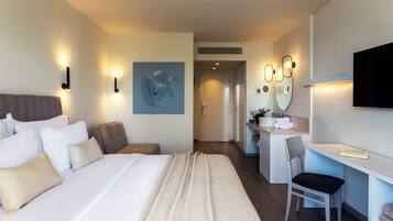 Una camera d'albergo moderna con un letto grande, una scrivania, una sedia e una TV.