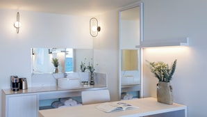 Un baño moderno con un tocador blanco, un espejo grande y una planta en maceta.