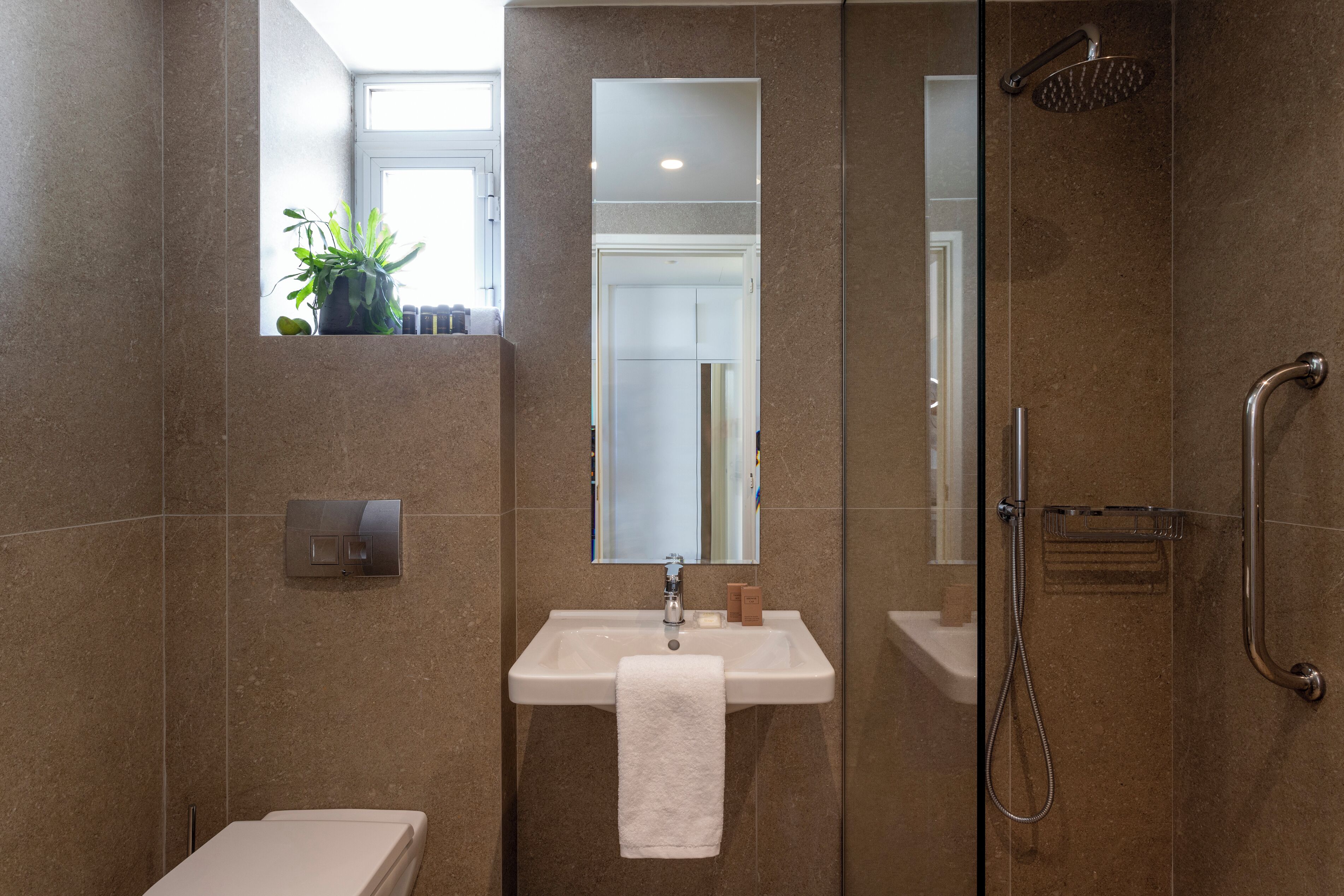 Un baño moderno con lavamanos, espejo y ducha.