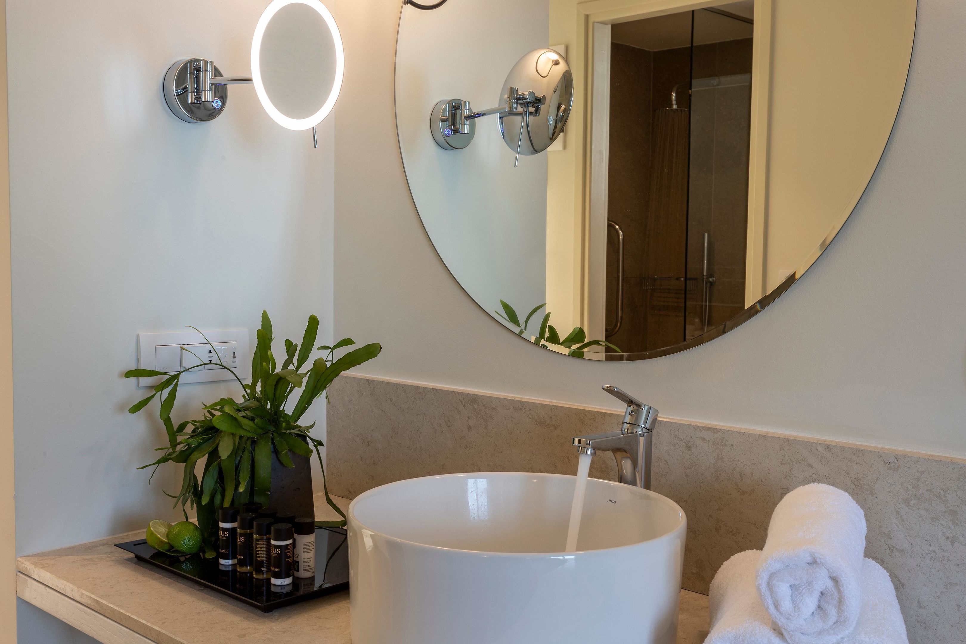 A modern bathroom with a round mirror, a white sink, and a towel.