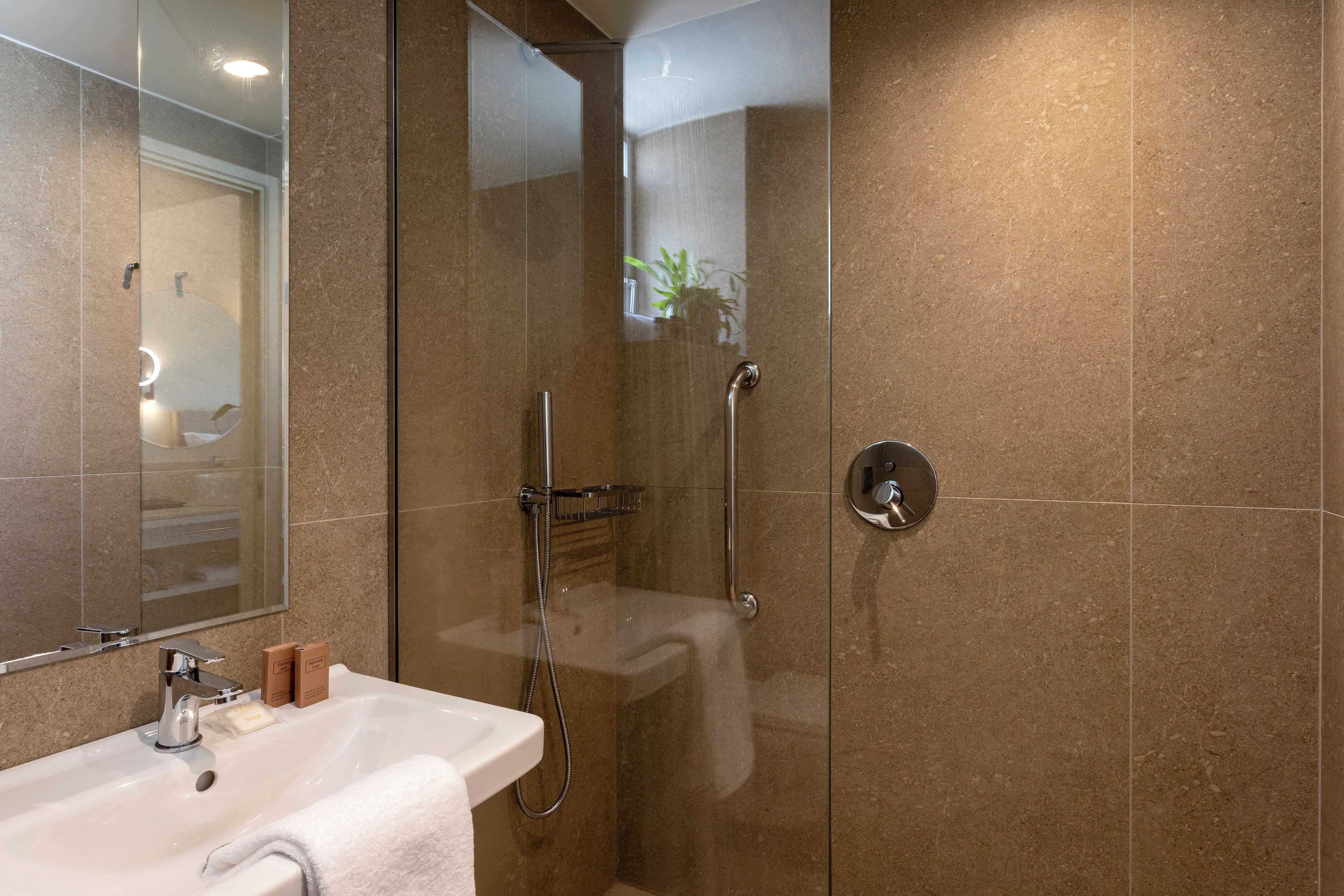 Un baño moderno con ducha de vidrio, lavamanos blanco y espejo.
