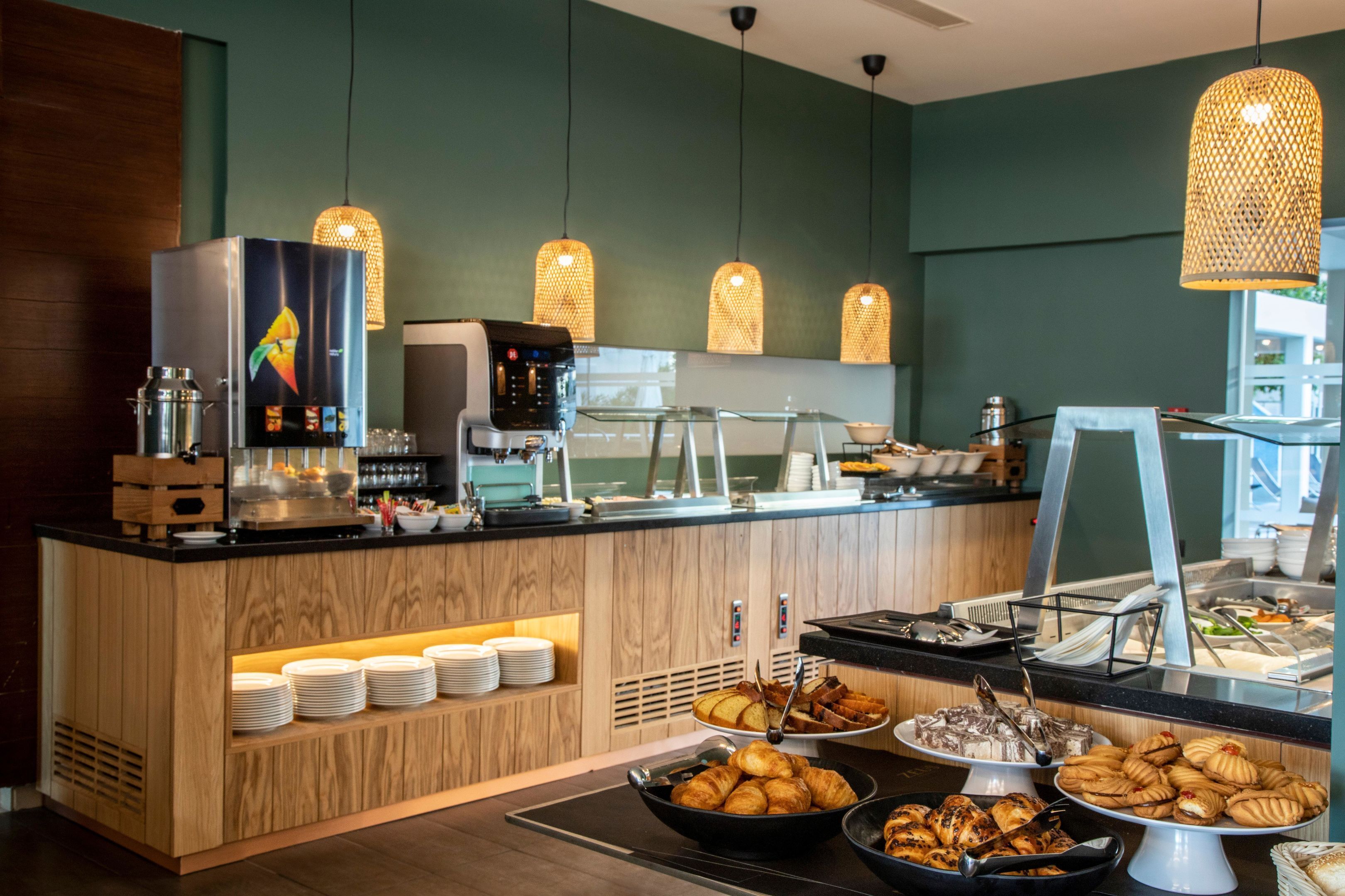 Zona de bufé con una máquina de café, diferentes opciones de comida y una estación de café.