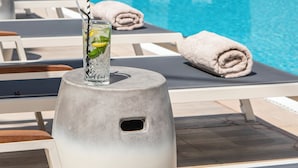 Zona de piscina con sillones de descanso, un bar y vistas a la piscina.