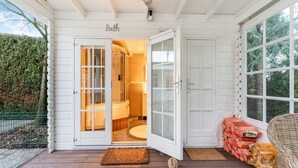 A wooden deck with a glass door leading to a bathroom. - Chalet Kieftveen with hot tub for four Person (Voorthuizen)