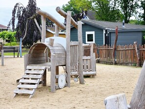 Explore the playground's fun features, including a slide, climbing section, and wheelbarrow.