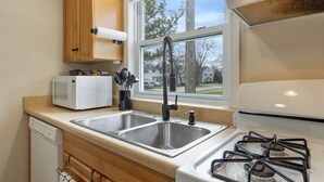 Una cocina compacta equipada con microondas, pileta doble y cocina a gas.