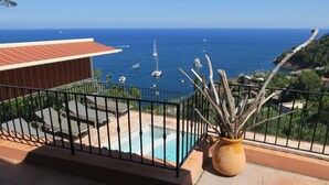 Un balcón con piscina, con vista al mar y barcos.