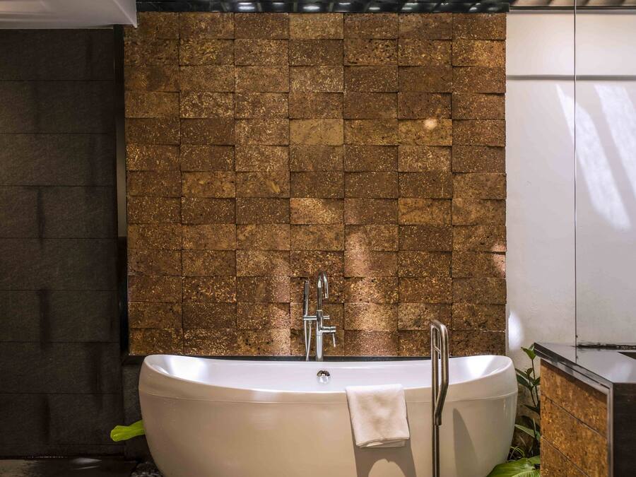 Ein modernes Badezimmer mit freistehender Badewanne, Steinwand und Decke mit Einbaustrahlern.