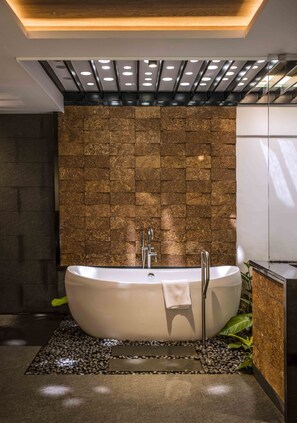 A modern bathroom with a freestanding bathtub, a stone wall, and a ceiling with recessed lighting. - Great Trails Wayanad by GRT Hotel (Vythiri)