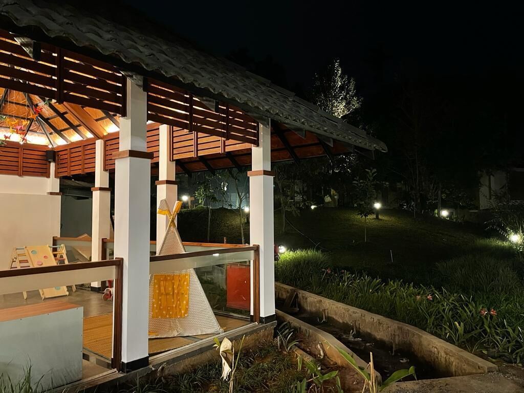 A well-lit outdoor area with a wooden structure, seating, and a small water feature.