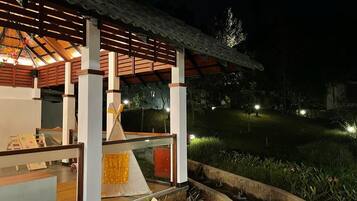 A well-lit outdoor area with a wooden structure, seating, and a small water feature.