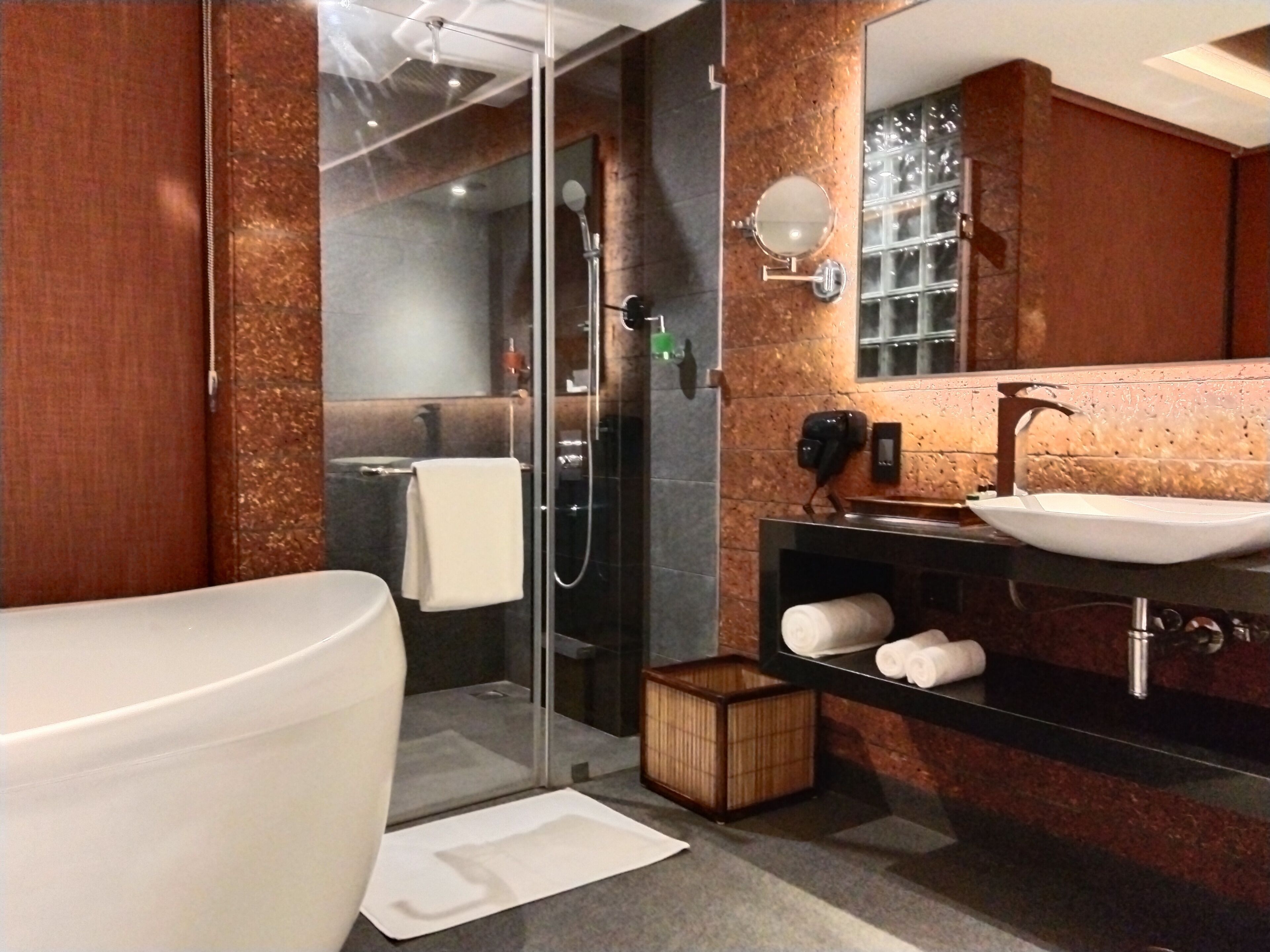 A modern bathroom with a glass-enclosed shower, a large white bathtub, and a black vanity with a vessel sink.