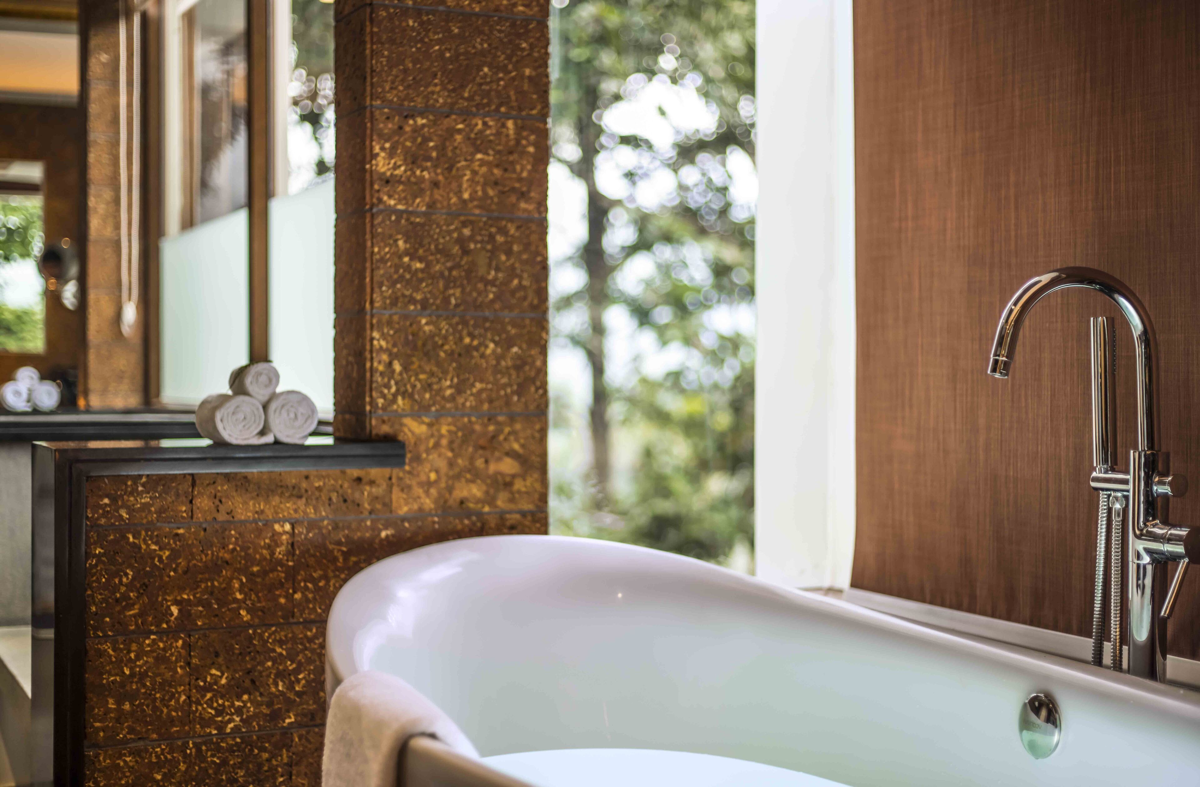 A modern bathroom with a freestanding bathtub, a wooden vanity, and a large mirror.