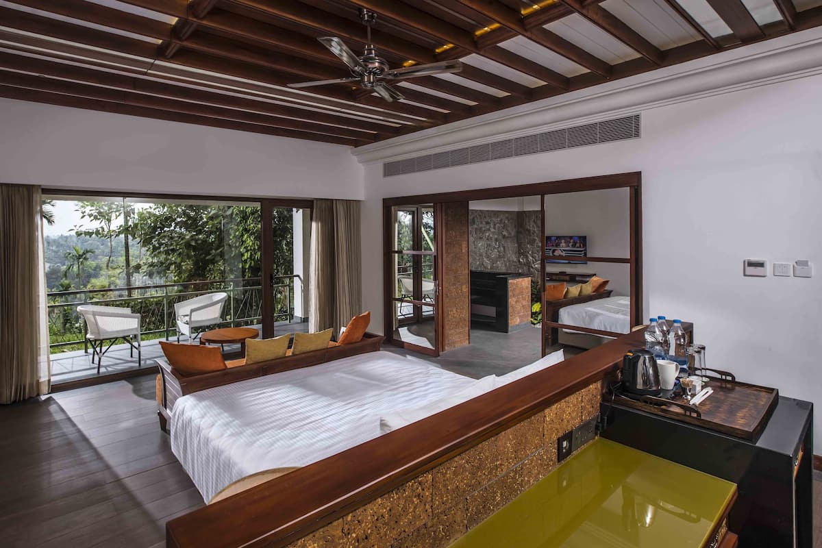Une chambre d’hôtel moderne avec un grand lit, un plafond en bois, un balcon avec des chaises et une télévision.