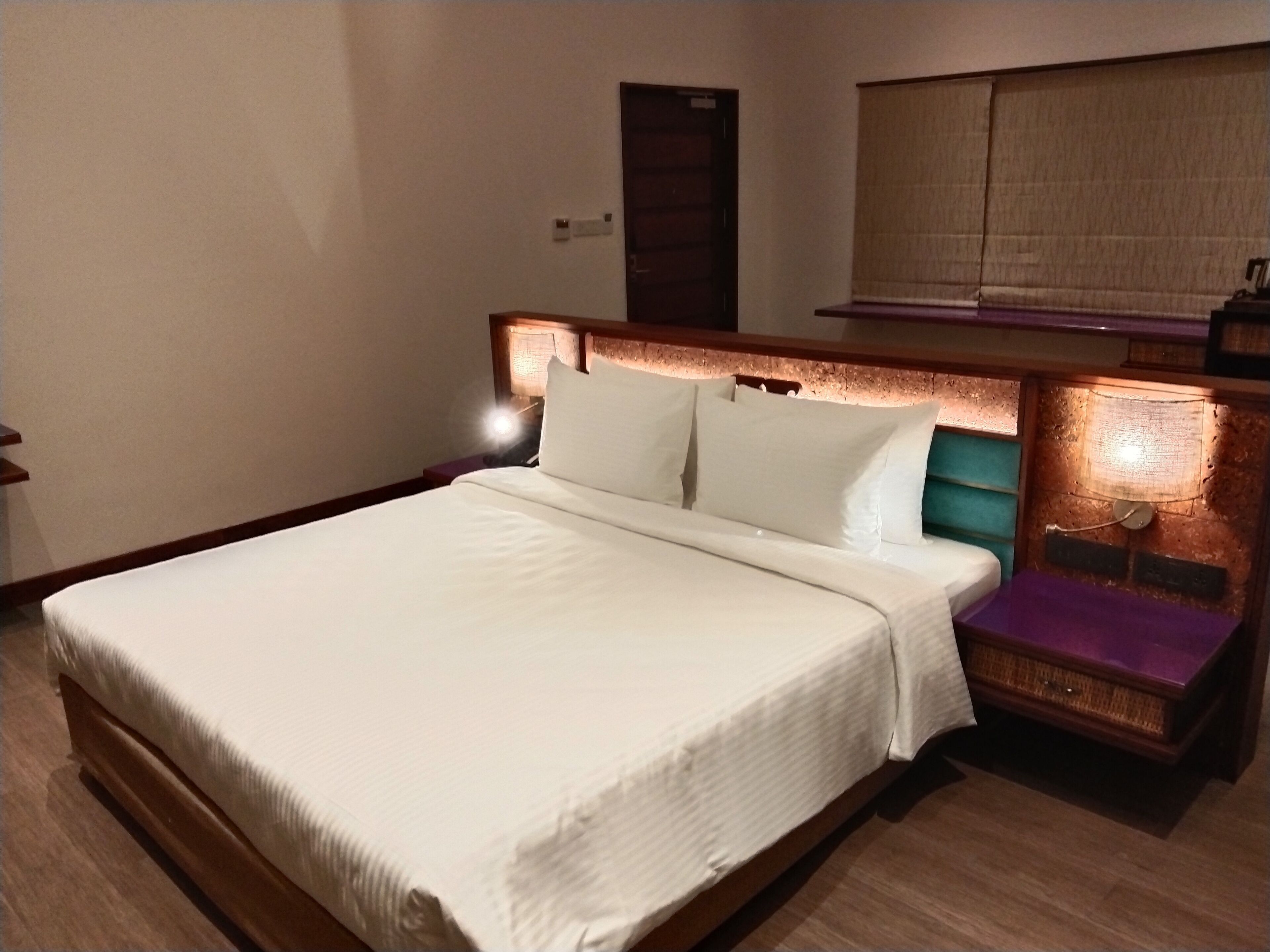 A neatly made bed with white linens in a hotel room.