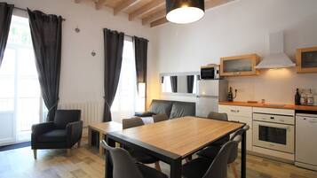 Een compacte keuken met een eethoek, met een houten tafel, stoelen en moderne apparaten.