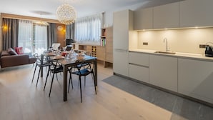 A modern living room with a dining area, a kitchen, and a large window with curtains.