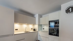A modern kitchen with white cabinetry, a built-in oven, and a sink.