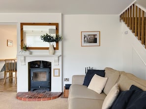 Una sala de estar con chimenea, sofá, escalera y un cuadro en la pared.