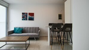 A modern living room with a grey sofa, teal pillows, a wooden coffee table, and two abstract paintings on the wall.