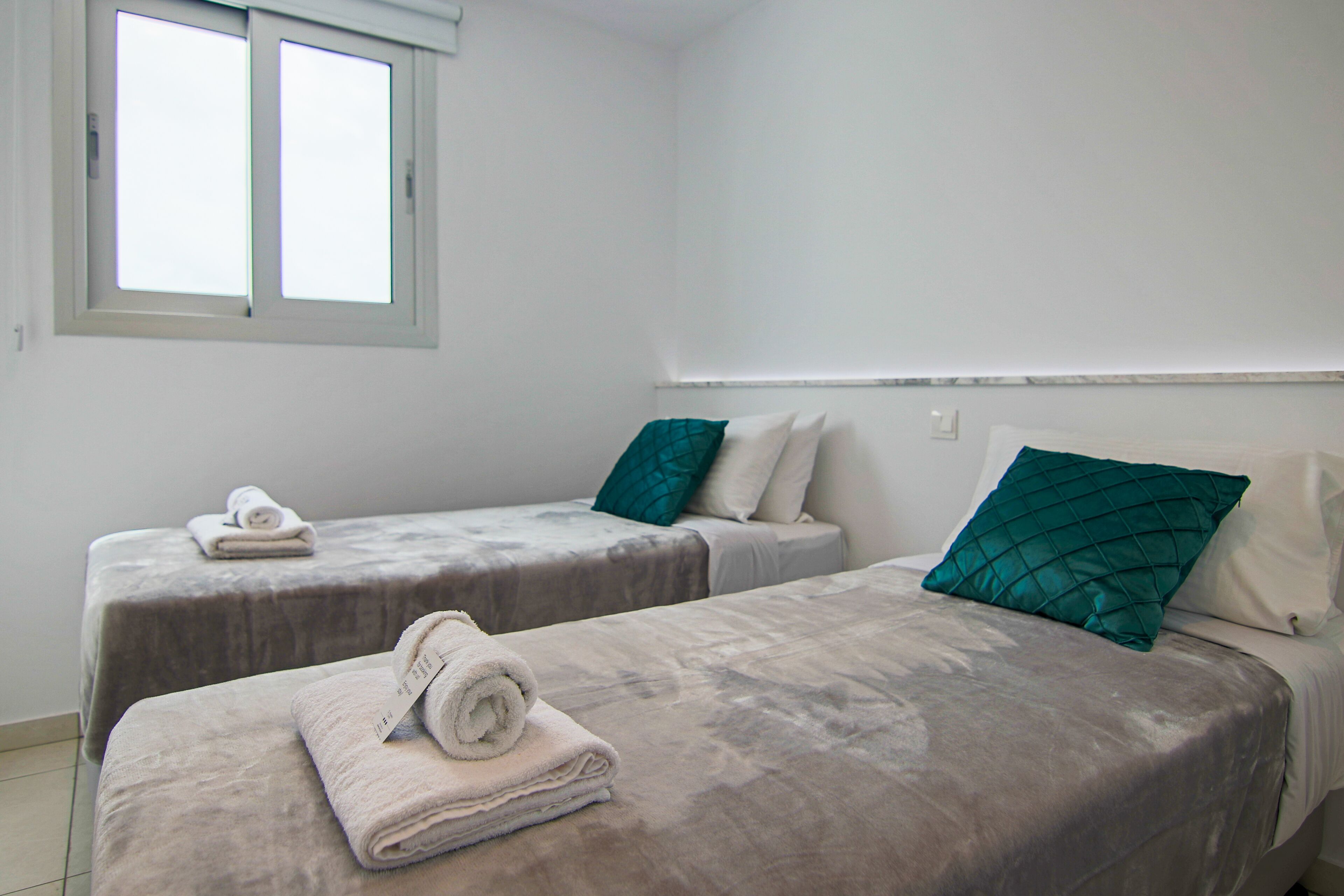 Une chambre d’hôtel avec deux lits, chacun étant équipé d’un oreiller et d’une serviette roulée.
