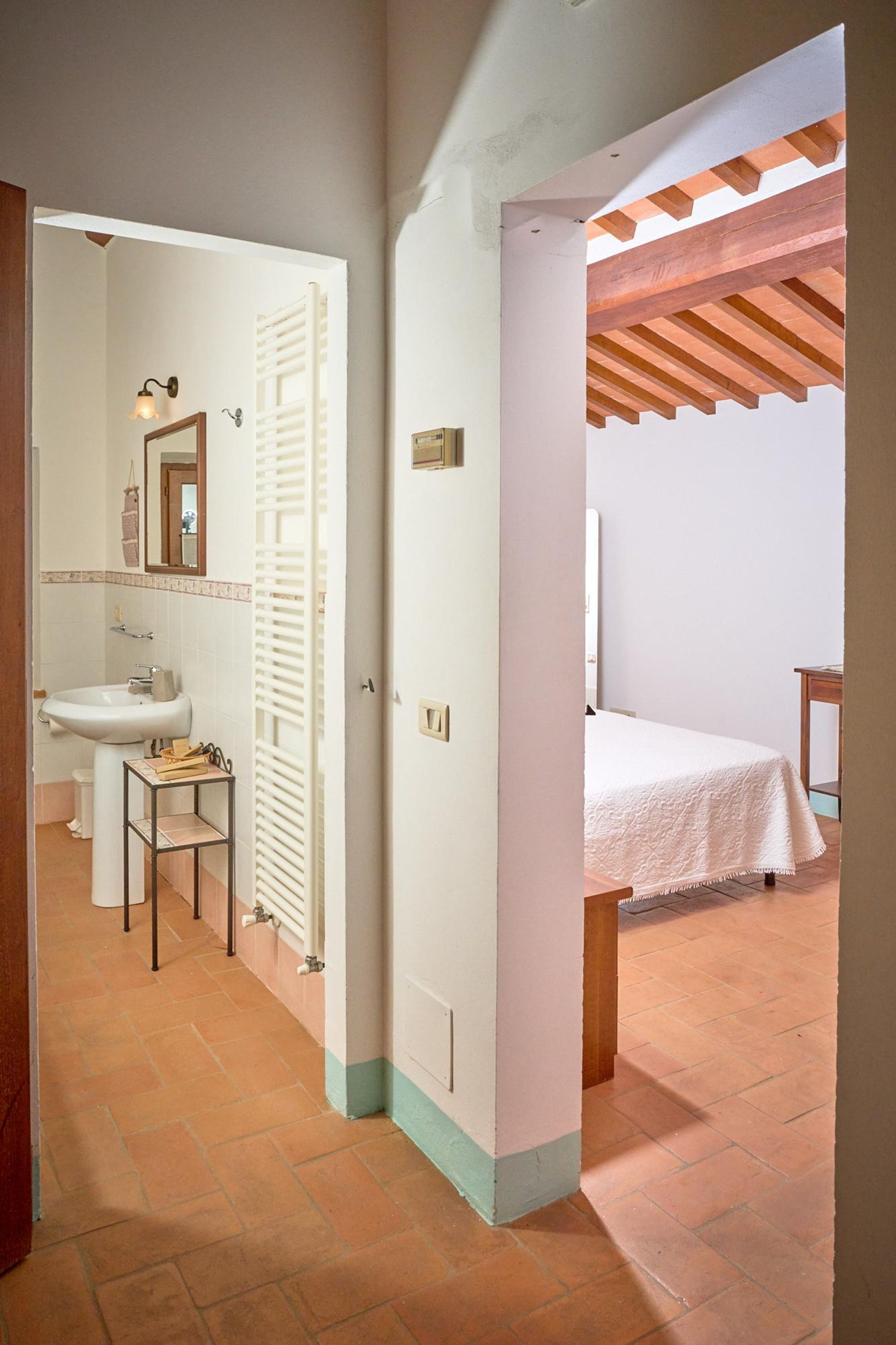 A bedroom with a bed, a wooden ceiling, and a white wall.