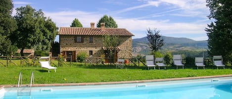 A stone house with a swimming pool and outdoor seating.