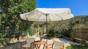 An outdoor patio with a table and chairs, a white umbrella, and potted plants. - Effie Apartment in (Corfu)