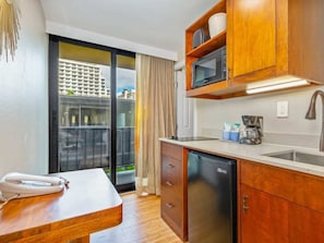 A compact kitchen with wooden cabinets, a built-in microwave, and a coffee maker. - Studio City View DLX Kitchenette A/C, and WiFi - Bamboo Waikīkī Hotel #410 (Honolulu)