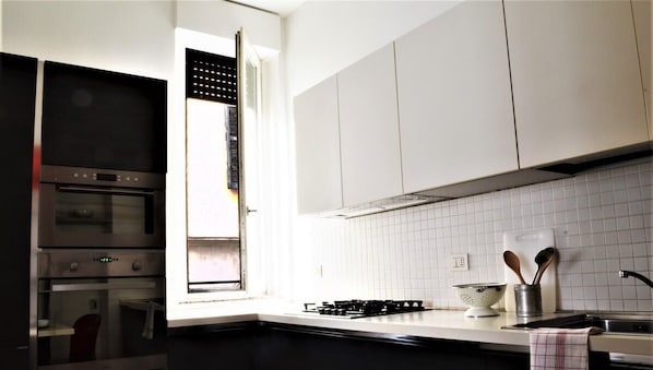 A modern kitchen with white cabinets, a gas stove, and a window with a view of the outdoors.