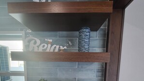 A kitchen counter with a coffee maker, a tray with cups and snacks, and decorative items on shelves.