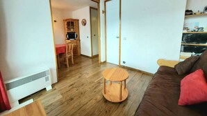 Ein Wohnzimmer mit einem braunen Sofa, einem runden Couchtisch und einem roten Tisch mit Stühlen.