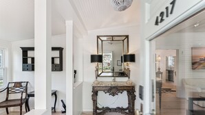 A hallway with a large mirror, a dark wooden console table, and a white door with the number 4217. - Renovated Cottage w/New Heated Swimming Pool at East Beach's 6th St. Access (Saint Simons Island)