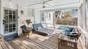 A covered outdoor area with a pool, wicker furniture, and a ceiling fan. - Renovated Cottage w/New Heated Swimming Pool at East Beach's 6th St. Access (Saint Simons Island)