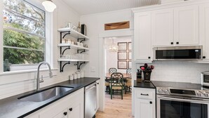 A modern kitchen with white cabinetry, a stainless steel sink, and a built-in oven. - Renovated Cottage w/New Heated Swimming Pool at East Beach's 6th St. Access (Saint Simons Island)